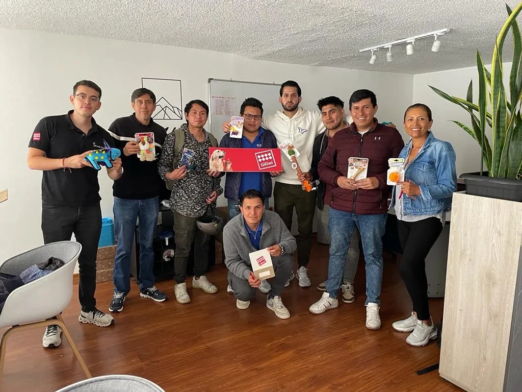 Grupo en una oficina mostrando juguetes GiGwi y un cartel de la marca
