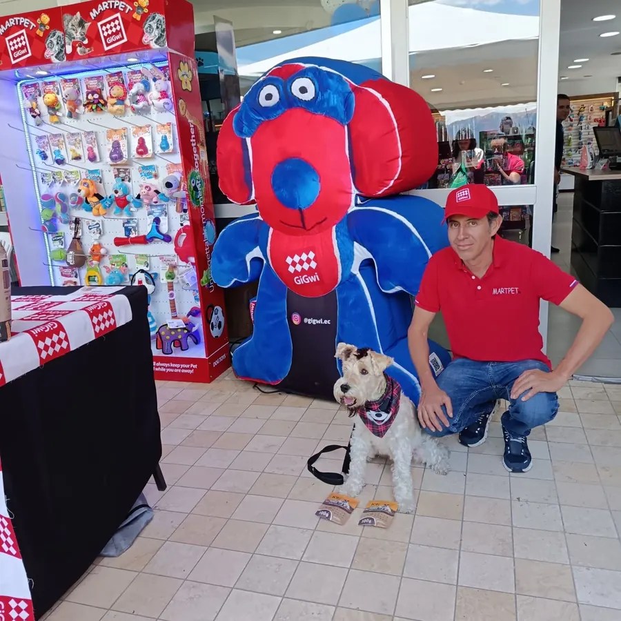 Asesor de MARTPET con un perro junto a la mascota inflable de GiGwi y un exhibidor iluminado en un punto de venta